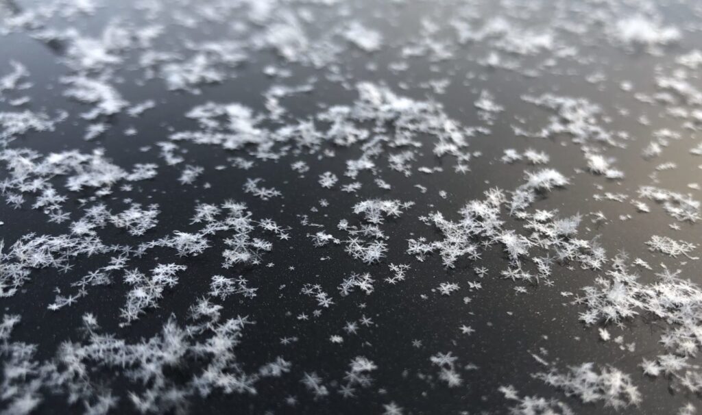 Flocos de neve em formato de estrela em superficie preta norte Finlândia
