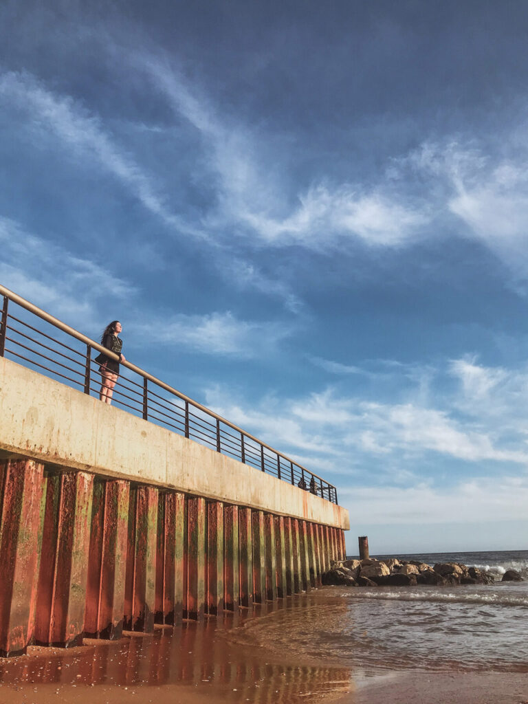 mulher olha de cima de um pier na praia do peneco em albufeira