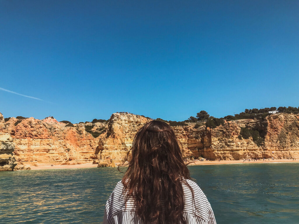 mulher de costas observando a costa do algarve vista do mar