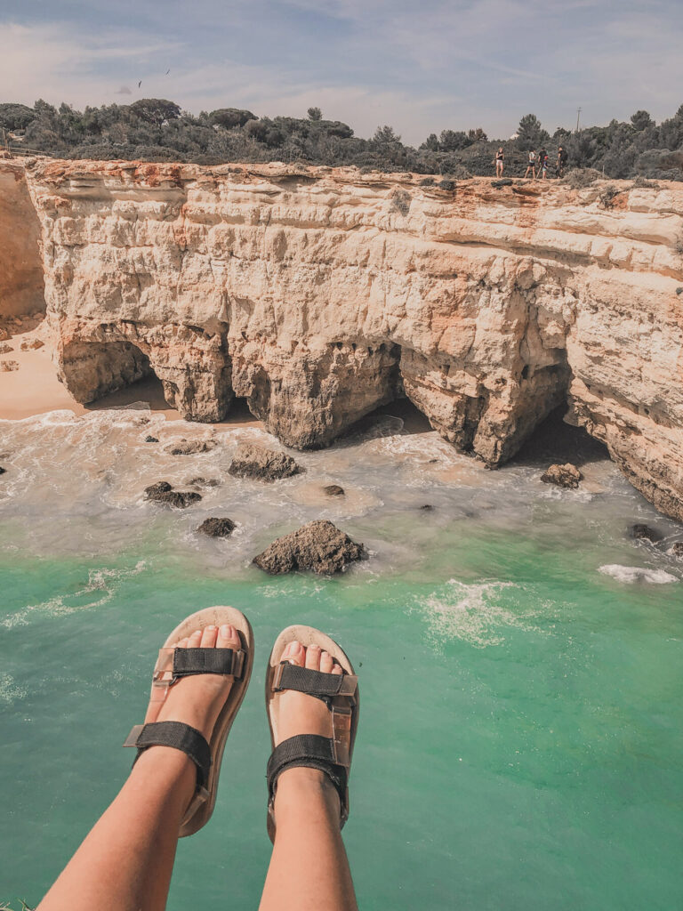 pés esticados com vista para o mar e as falésias da praia de albandeira no algarve em portugal